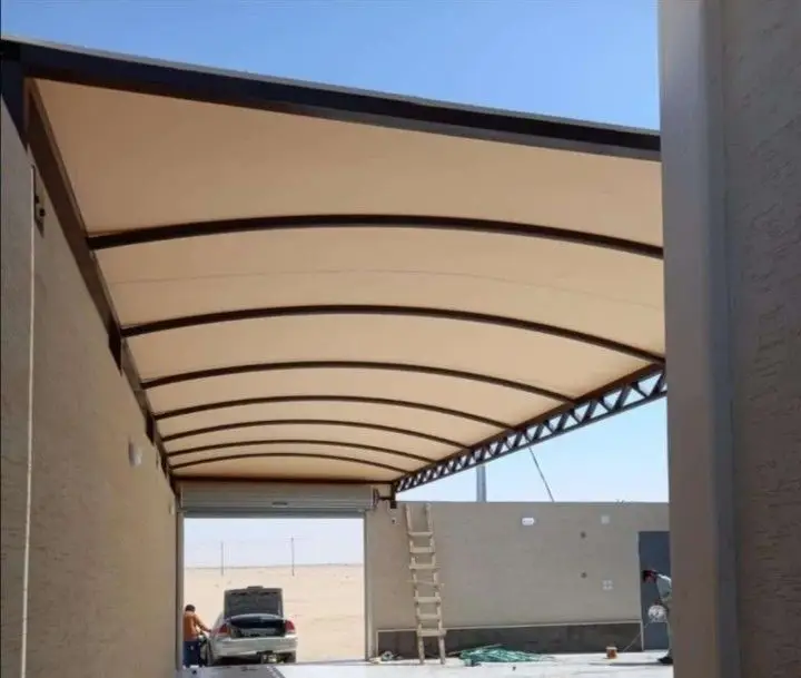 "مظلة سيارات مقوسة حديثة مثبتة بين جدارين بتصميم قوي توفر حماية كاملة للسيارة من الشمس والحرارة في جدة."