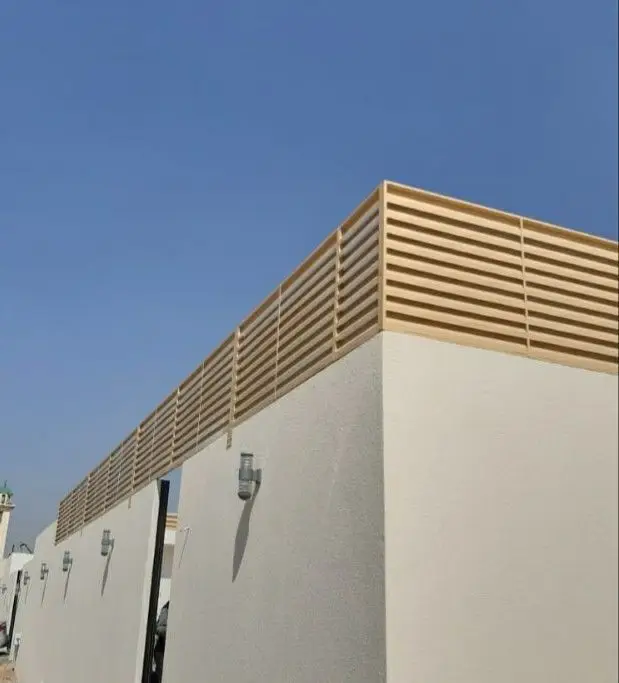 "سواتر خشبية حديثة باللون الخشبي الفاتح مثبتة أعلى جدار خارجي لتأمين الخصوصية والحماية للمنازل في جدة."